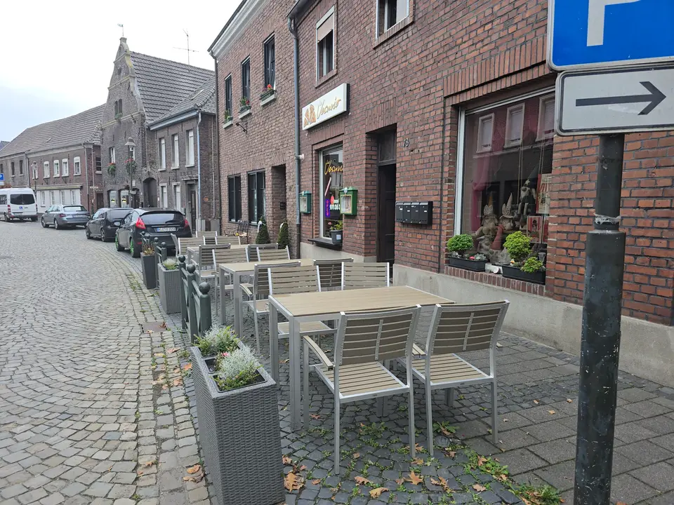 Tische und Stühle vor der Pizzeria in der gepflasterten Feldstraße.