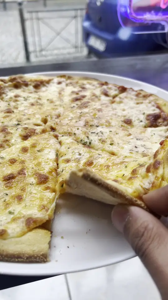 Eine Pizza mit viel Käse, gerade angeschnitten.
